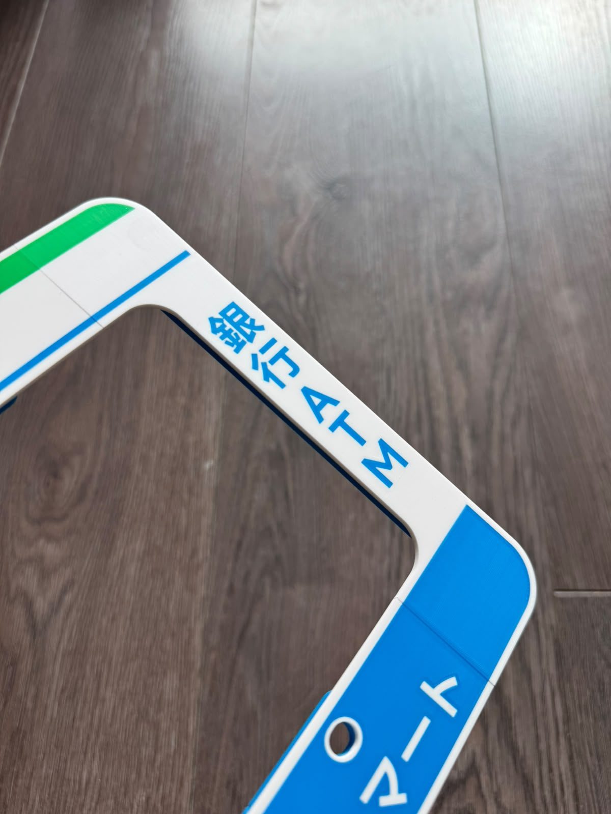 Close-up of the right side of the Family Mart license plate frame showing the 銀行 ATM rail and マート lettering